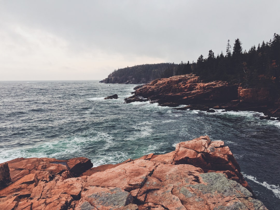 brown rocky mountain beside body of water during daytime