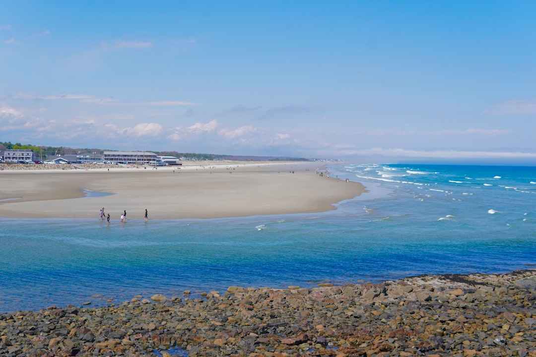 Wide sandy beach with blue ocean waves and distant town.