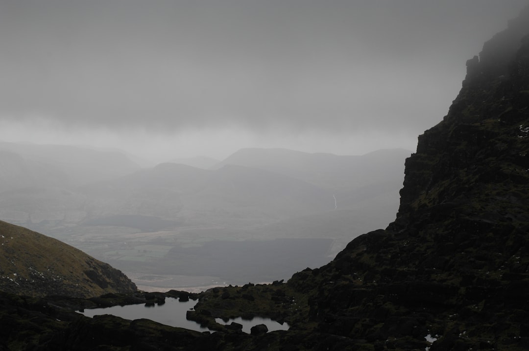 a foggy mountain landscape with a lake in the foreground
